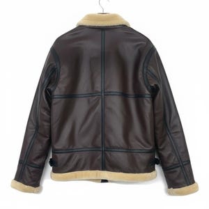 May include: Brown faux leather jacket with a cream-colored shearling collar and trim. The jacket features black trim and stitching details, with a classic aviator style. The back view shows the jacket hanging on a hanger.