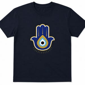 以下が含まれることがあります： ネイビーブルーのTシャツ。中央にハムサハンドのデザイン。ハムサハンドは青色で、金と白のアクセント、中央に目のシンボルがあります。デザインはシャツの前面に配置されています。