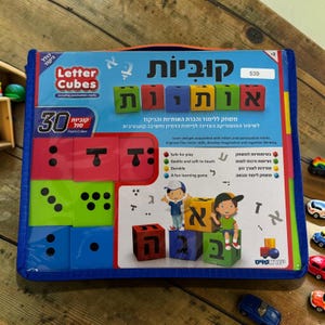 May include: A blue carrying case containing a set of 30 foam letter cubes. The cubes are red, green, and blue. The case has the words "Letter Cubes" and "Including punctuation marks" printed on it. The set is designed to help children learn letters and punctuation.