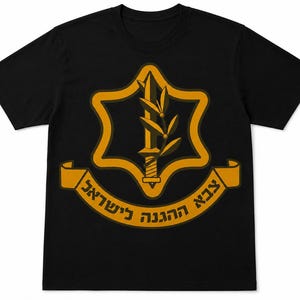 Puede incluir: Camiseta negra con un emblema dorado que representa una espada, una rama de olivo y una estrella. El emblema está enmarcado por un borde dorado y una pancarta con texto hebreo. La camiseta está hecha de un material suave y cómodo.
