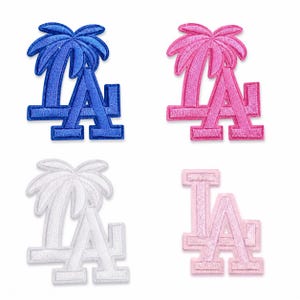 Pode incluir: Quatro emblemas bordados com as letras LA. O superior esquerdo é azul com uma palmeira, o superior direito é rosa com uma palmeira, o inferior esquerdo é branco com uma palmeira e o inferior direito é um logótipo LA rosa claro sem palmeira.