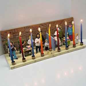 Może przedstawiać: Menora chanukowa z dziewięcioma zapalonymi świecami w różnych kolorach. Menora przedstawia małe figurki ludzi i tło z kamiennej ściany. Świece znajdują się w mosiężnych uchwytach, a podstawa jest ozdobiona symbolami Gwiazdy Dawida.