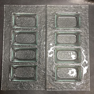 May include: Two clear glass serving platters, each with four rectangular compartments. The platters have a textured surface and a slight green tint around the edges of the compartments. Suitable for serving appetizers or small portions.
