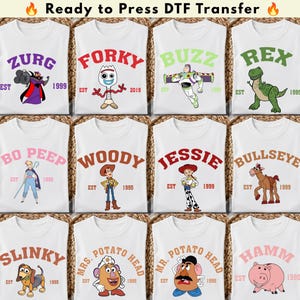 May include: A collection of twelve white DTF transfer sheets featuring various cartoon characters from the Toy Story franchise. Each sheet displays a character name in an arched font, the character illustration, and an established year date.