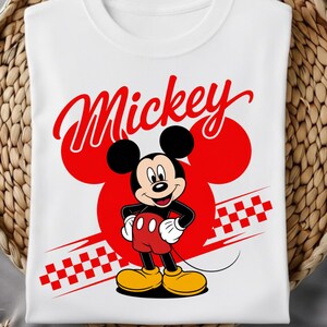 Op de afbeelding: Wit T-shirt met een cartoonafbeelding van Mickey Mouse. Het woord "Mickey" staat in rode letters boven het personage, met een rode Mickey Mouse-hoofdomtrek erachter. Het shirt heeft ook de tekst "Ready to Press DTF Transfer".