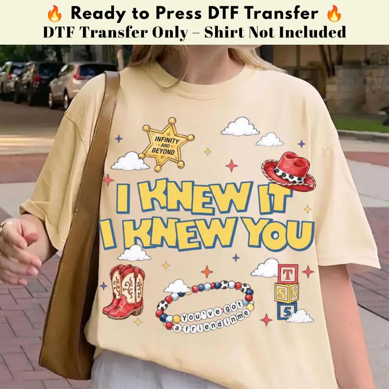 以下が含まれることがあります： クリーム色のTシャツ。I KNEW IT I KNEW YOUの文字、INFINITY AND BEYONDと書かれた金色の保安官バッジ、赤いカウボーイハット、赤いカウボーイブーツ、YOU'VE GOT A FRIEND IN MEと書かれたビーズブレスレット、積み木のグラフィックがプリントされています。