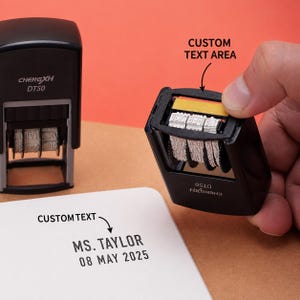 Könnte beinhalten: Zwei schwarze selbstfärbende Stempel mit der Aufschrift CHENGXH DT50. Ein Stempel wird gehalten und zeigt die internen rotierenden Datumsräder sowie einen gelben Streifen im Textbereich. Der andere hat MS. TAYLOR 08 MAY 2025 auf Papier gedruckt.