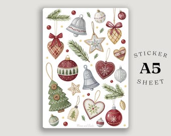 Puede incluir: Hoja de pegatinas A5 con ilustraciones en acuarela de adornos navideños. Incluye campanas, estrellas, corazones y bolas en rojo, verde y dorado, junto con ramitas de hoja perenne. El texto "Sticker A5 Sheet" es visible.