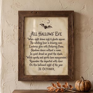 May include: A framed wall art piece featuring a poem titled All Hallows' Eve with a bat and crescent moon illustration. The text reads: When night draws nigh & ghosts appear, The witching hour is drawing near. Lanterns glow with flickering flame, Shadows dance without a name. In quiet dread we greet the shade, While spooks and spirits have masqueraded. Remember the departed with cheer On this hallowed night of the year. 31 OCTOBER.