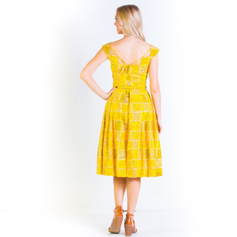 May include: A yellow midi dress with a checkered pattern and a tie at the back. The dress has a fitted bodice and a full skirt.