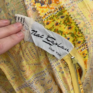 May include: Yellow and orange floral print dress with a yellow zipper and a white label that reads "Nat Kaplan New York".