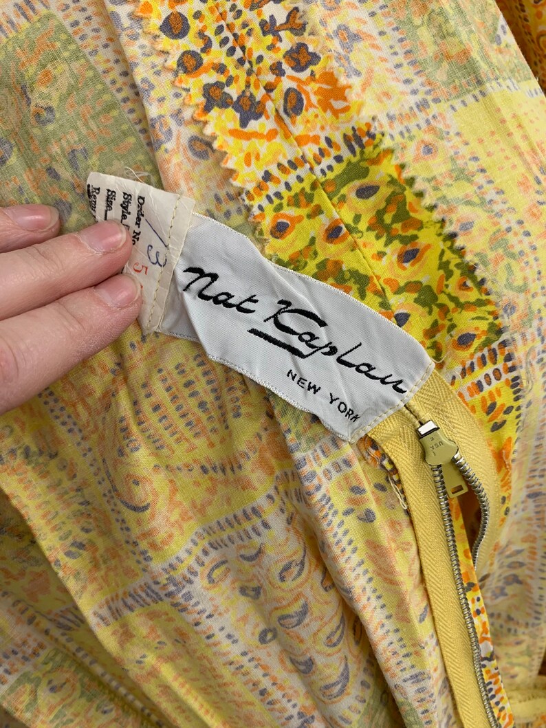 May include: Yellow and orange floral print dress with a yellow zipper and a white label that reads "Nat Kaplan New York".