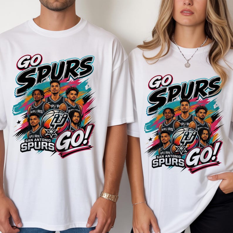 May include: White t-shirts with a colorful graphic featuring the text "GO SPURS" and a team logo. The design includes images of basketball players and the words "SAN ANTONIO SPURS GO!"