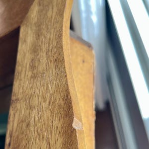 May include: Close-up of a wooden furniture piece, showcasing the natural wood grain and warm tones. The curved edge and joinery details are visible, highlighting the craftsmanship. The wood has a light brown color.