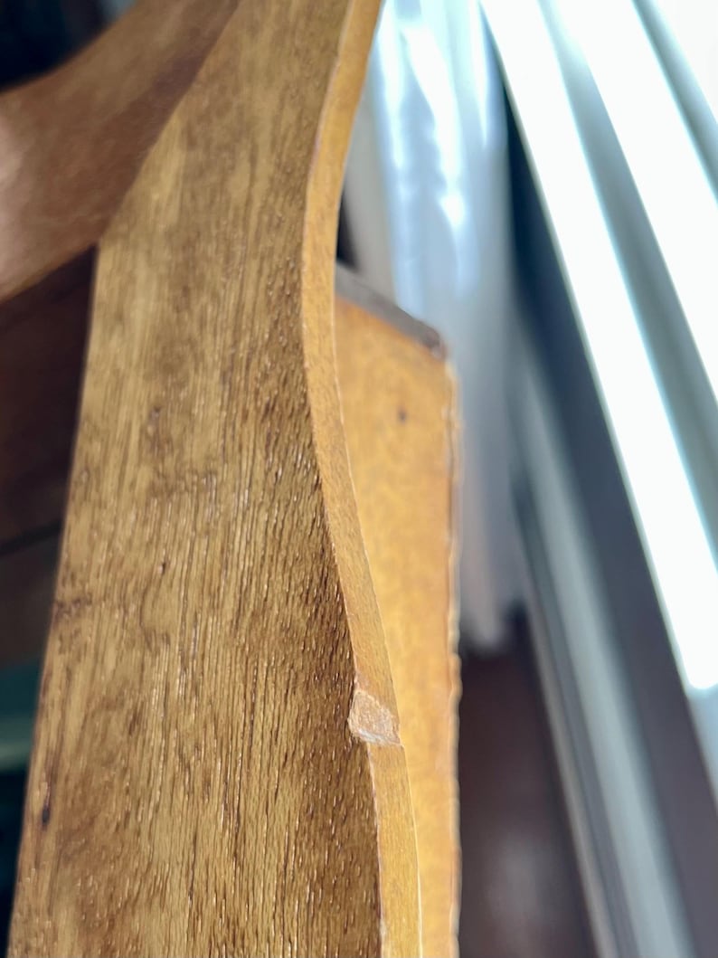 May include: Close-up of a wooden furniture piece, showcasing the natural wood grain and warm tones. The curved edge and joinery details are visible, highlighting the craftsmanship. The wood has a light brown color.