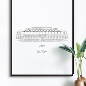 May include: Black framed art print featuring a line drawing of a stadium. The stadium has a detailed roof and facade. Below the image, the text reads "IBROX GLASGOW". The print is displayed on a white background.