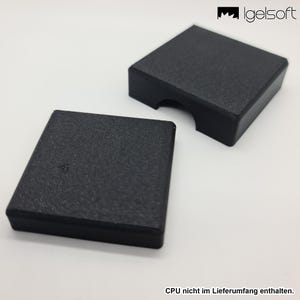 May include: Two black, textured, square-shaped cases. One case has a curved cutout on one side. The cases are on a white surface. The text "CPU nicht im Lieferumfang enthalten" is at the bottom.