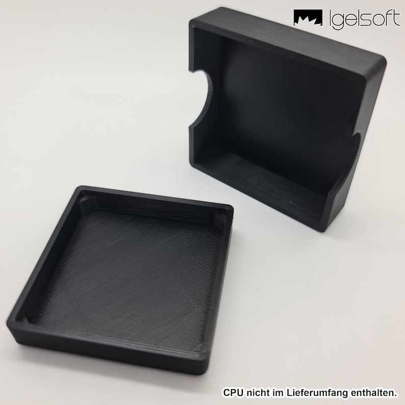 May include: A black, rectangular case with a matching lid. The case has a curved cutout on one side. The lid is separate, revealing the interior. The case is likely designed to hold small items.