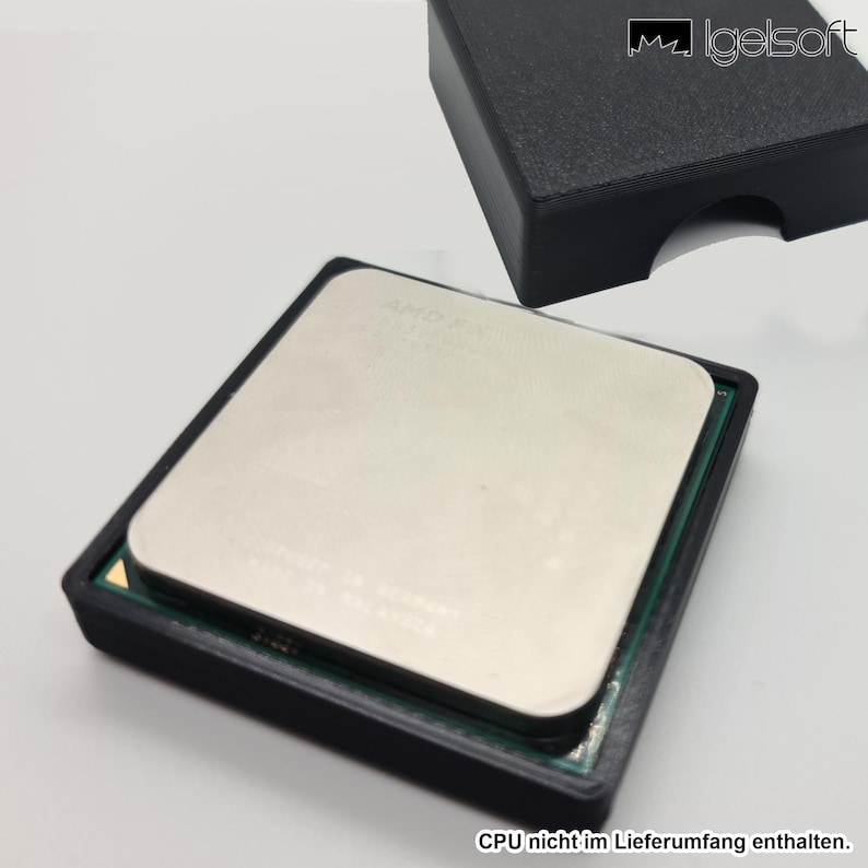 May include: A silver-colored AMD CPU is set in a black plastic holder. The CPU has a rectangular shape with a metallic surface. A second black holder is in the background. The text "CPU nicht im Lieferumfang enthalten" is at the bottom.