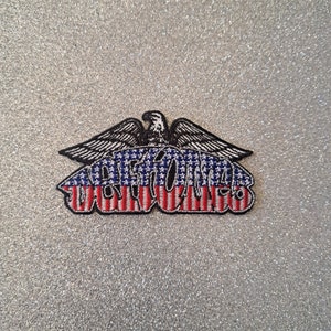 May include: Embroidered patch featuring an eagle with outstretched wings above the text "VOTE 76" in a patriotic design. The text is in red, white, and blue, with a black border. The patch is likely for clothing or accessories.
