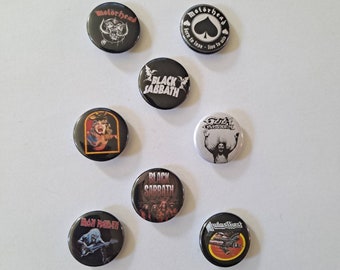 May include: A collection of black round pinback buttons featuring various rock band logos, including Motörhead, Black Sabbath, and Judas Priest. The buttons have colorful graphics and text, with a glossy finish. Ideal for fans of classic rock and heavy metal music.