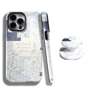 Op de afbeelding: Een telefoonhoesje, telefoonhouder en zijaanzicht van een telefoonhoesje met een patchwork-ontwerp in blauw- en wittinten. De telefoonhoes heeft een citaat: "may Jesus be seen in me in spite of me."