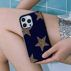 May include: A navy blue phone case featuring a leopard print star pattern. The case has a glossy finish and a protective design. The case is designed for a smartphone with multiple camera lenses.