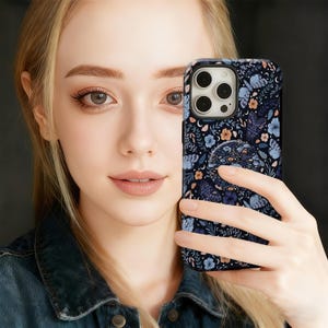 May include: A black smartphone case with a floral and moth pattern in shades of blue, orange, and white. The case has a built-in pop socket with a matching design. The phone case is a protective accessory.