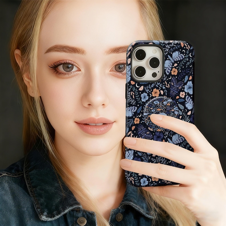 May include: A black smartphone case with a floral and moth pattern in shades of blue, orange, and white. The case has a built-in pop socket with a matching design. The phone case is a protective accessory.