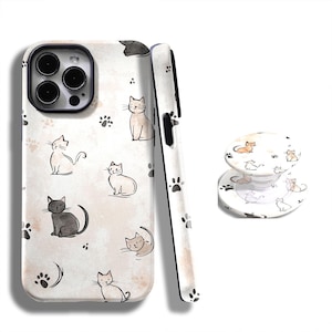 Peut inclure: Une coque de téléphone blanche et un support de téléphone avec un motif répété de chats de dessins animés et d'empreintes de pattes. Les chats sont dans diverses poses et couleurs, dont le gris, le noir et le beige. La coque est conçue pour un smartphone.