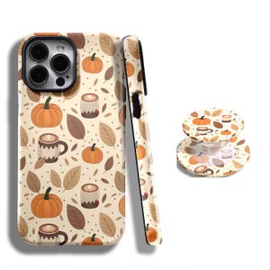 May include: A beige phone case and phone grip featuring a fall-themed pattern. The design includes orange pumpkins, brown leaves, and coffee mugs. The phone case is shown from multiple angles.