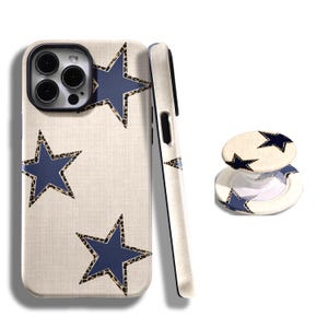 May include: A phone case and pop socket set. The phone case is off-white with three navy blue stars outlined with a leopard print pattern. The pop socket has a matching design with two navy blue stars.