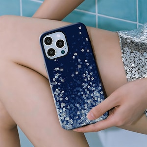 May include: A dark navy blue smartphone case featuring a gradient pattern of small, white, four-petaled flower blossoms that become denser towards the bottom edge. The case includes a cutout for a triple-lens camera system and a flash.