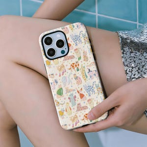 May include: A phone case with a cream background and a colorful pattern of various cat illustrations. The cats are in different poses and colors, including blue, green, and orange. The case has a black border and a camera cutout.