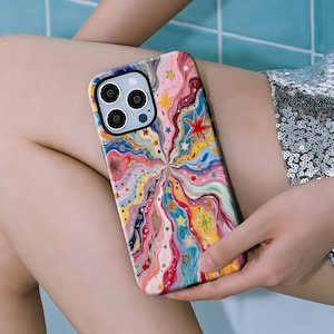 Puede incluir: Una funda de teléfono colorida con un diseño vibrante y arremolinado con estrellas y formas abstractas en tonos de rosa, amarillo, azul y rojo. La funda tiene un borde negro y un recorte para la cámara.