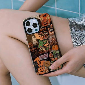 May include: A black and orange Halloween-themed phone case with various illustrations, including pumpkins, ghosts, and the text "Halloween Costume Party". The case has a glossy finish and a protective design.