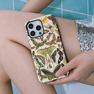 Puede incluir: Una funda de teléfono con una ilustración vintage de mariposas en varios colores, incluyendo verde, amarillo y marrón. La funda tiene un fondo beige y un borde negro, mostrando un diseño detallado de diferentes especies de mariposas.