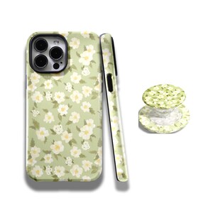 May include: A phone case and a phone grip featuring a floral pattern. The case and grip have a light green background with white and yellow flowers. The phone case is shown from the front and side.