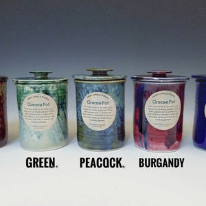 Pode incluir: Cinco potes de gordura de cer&acirc;mica com tampas em diferentes cores: marrom, verde, azul pav&atilde;o, bord&ocirc; e azul. Cada pote tem um r&oacute;tulo que diz "Grease Pot".