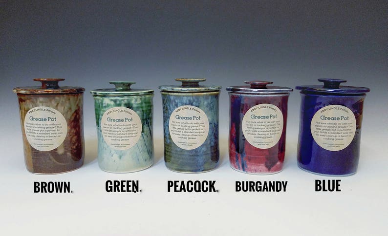 Pode incluir: Cinco potes de gordura de cer&acirc;mica com tampas em diferentes cores: marrom, verde, azul pav&atilde;o, bord&ocirc; e azul. Cada pote tem um r&oacute;tulo que diz "Grease Pot".