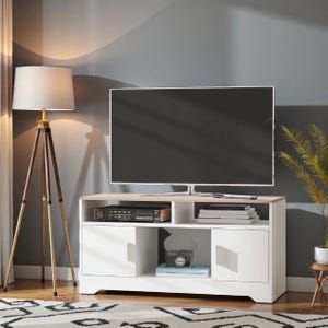 Könnte beinhalten: Ein weißer und holzfarbener TV-Schrank mit einem großen Fernseher mit schwarzem Bildschirm. Der Schrank hat zwei Türen, offene Regale und eine hellfarbige Oberseite. Eine Stativ-Stehlampe mit beigem Schirm steht links.