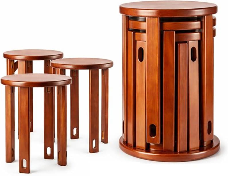May include: A set of five round wooden stools with a smooth, reddish-brown finish. Each stool features four straight legs with a small oval cutout near the base. The stools are designed to stack vertically into a single cylindrical tower unit.