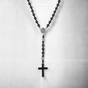 Puede incluir: Collar de rosario negro con cuentas redondas y oscuras y un colgante de cruz negro. El collar incluye una pieza central plateada y cuentas m&aacute;s peque&ntilde;as. Las cuentas tienen aproximadamente 0,8 cm de di&aacute;metro.
