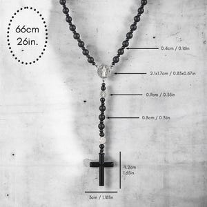 Puede incluir: Collar de rosario negro con un colgante de cruz. El collar mide 66 cm de largo y presenta cuentas negras y detalles plateados. La cruz mide 4,2 cm de alto y 3 cm de ancho.