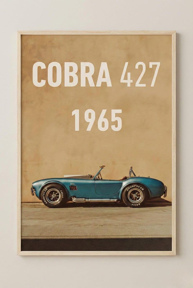 Puede incluir: Impresi&oacute;n enmarcada de un coche descapotable Cobra 427 azul de 1965. El coche est&aacute; aparcado sobre una superficie de hormig&oacute;n, con un fondo beige. Las palabras "COBRA 427" y "1965" est&aacute;n en texto blanco en la parte superior.