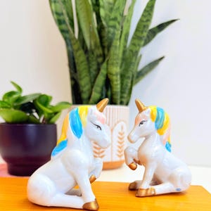 May include: A set of three ceramic nesting bowls in shades of blue, green, and white. The bowls feature a speckled glaze and a simple, modern design. The largest bowl measures approximately 8 inches in diameter.