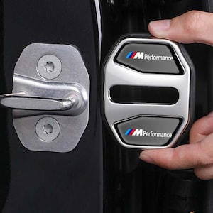 Puede incluir: Una taza de cerámica blanca con asa negra y el texto "But First, Coffee" en negrita negra. La taza se encuentra sobre un fondo borroso, sugiriendo un ambiente acogedor.