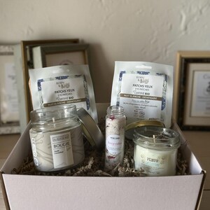 Peut inclure: Un coffret cadeau contenant des produits de beauté. Il comprend deux paquets de patchs pour les yeux, deux bougies en pots de verre et un petit flacon de sels de bain. Les bougies portent les inscriptions "BOUGIE" et "FLEUR DE COTON".