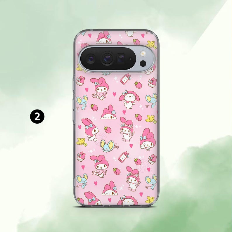 May include: A pink phone case featuring a repeating pattern of cartoon characters, strawberries, and hearts. The case has a clear border and a camera cutout. The characters are in pink, blue, and yellow.