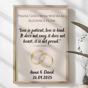 Puede incluir: Un cuadro con una impresión de boda con el texto "Love is patient, love is kind." y los nombres "Anna & David" con la fecha "26.09.2025". La impresión presenta dos anillos de boda dorados.